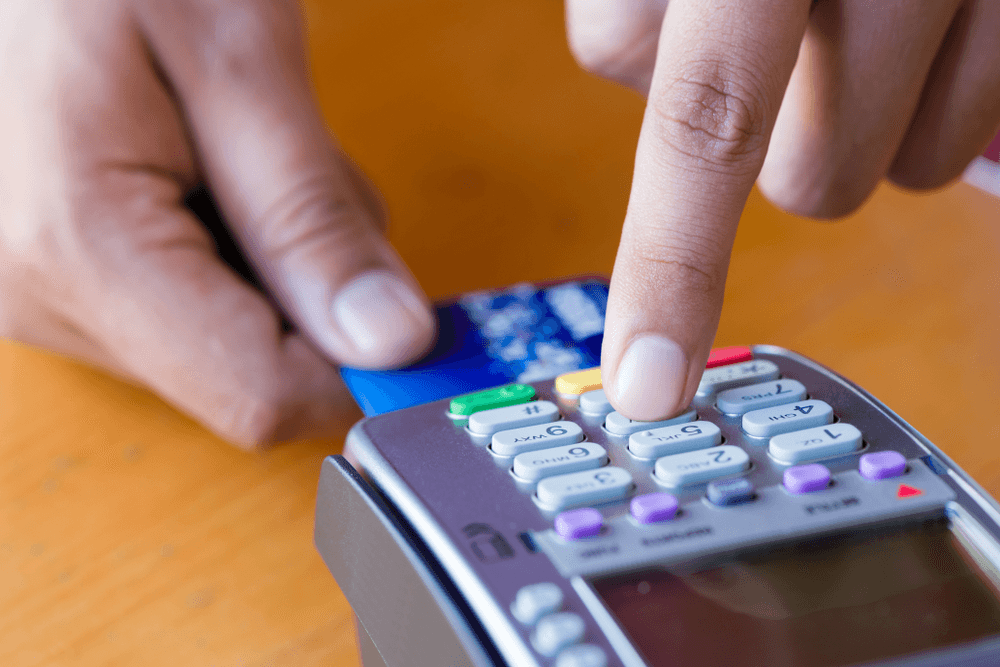 fingers punching numbers on a credit card processor