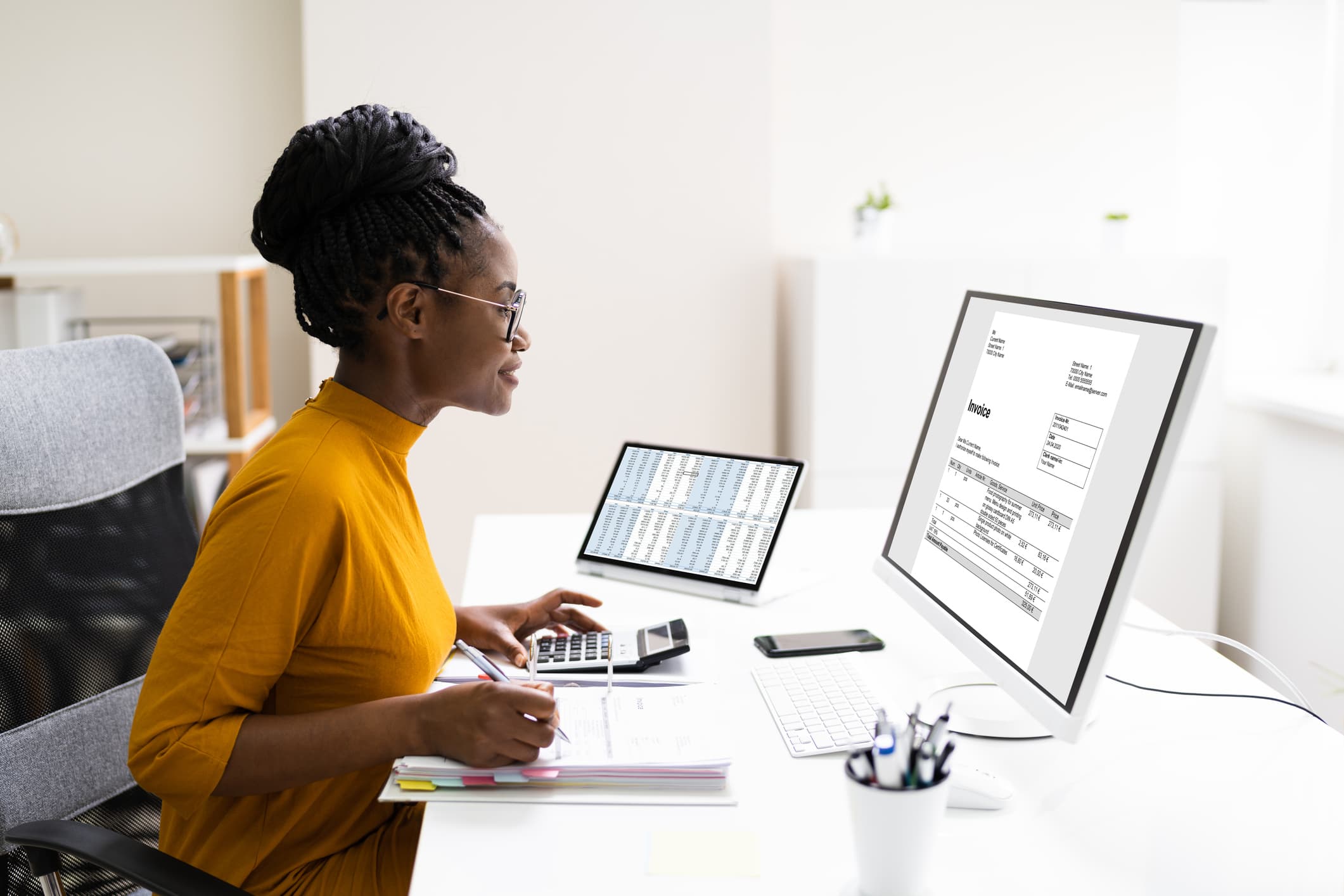 Accountant using a computer and a calculator at a desk